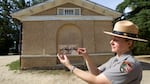 A woman in a National Park Service uniform holds up a Civil War-era photo of Selina Norris Gray, at the site where it was taken at what is now Arlington National Cemetery.