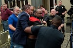 Police remove a man from the town hall as onlookers watch.