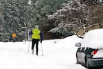 A skier heads down a residential street where about six inches of snow fell overnight Thursday, Jan. 6, 2022, in Bellingham, Wash. The latest storm to hit the Pacific Northwest brought flood warnings, the shutdown of a major mountain pass, school closures and icy roads.