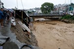 People gather at the edge of the Bagmati River in spate after heavy rains in Kathmandu, Nepal, Saturday, Sept. 28, 2024.