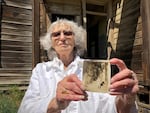 Ninety-year-old Ellen Simmons holds photo of herself standing on the porch of the Nelson House in 1929.