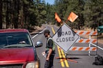 Wesley, a Koch Security Group guard contracted with the Oregon Department of Forestry who identified by first name only, speaks with a resident, who lives in a Level 2 “Get Set” evacuation zone, at a road block for the Akawa Butte Fire, just north of Sisters, Ore., on a windy afternoon on July 25, 2026.