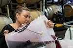 Bree Stock, co-owner of Limited Addition Wines in Gaston, Ore., pours cabernet franc juice into a storage vessel on Oct. 26. Stock said the short harvest window in 2025 caused complications in managing storage and fermentation space.
