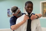 A person helps a man with his tie.