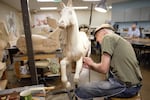 An artist works on a new horse March 29, 2023, at the Albany Carousel Museum. Many people come not only to ride the carousel but also to watch the artists who spend hours carving and painting carousel animals there.