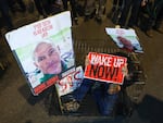 A man sits in a cage with portraits of 47-year-old Israeli hostage Elad Katzir as relatives and supporters of Israeli hostages stage a demonstration in Tel Aviv on March 26.