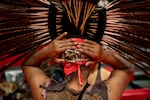 Jaime Uribe, a Mexica Aztec man, puts on his headdress made of red pheasant feathers and a jaguar head at the Veterans Powwow at Chemawa Indian School in Salem, Ore., on Nov. 8, 2025.