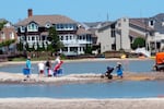 Beachgoers cross over one of numerous large pools of water that formed on the beach in Margate, N.J., after heavy rains in July 2017. The water was blocked from draining into the ocean by sand dunes built as part of a storm protection program that Margate residents vigorously fought, claiming that the dunes would cause exactly the type of standing water that occurred.