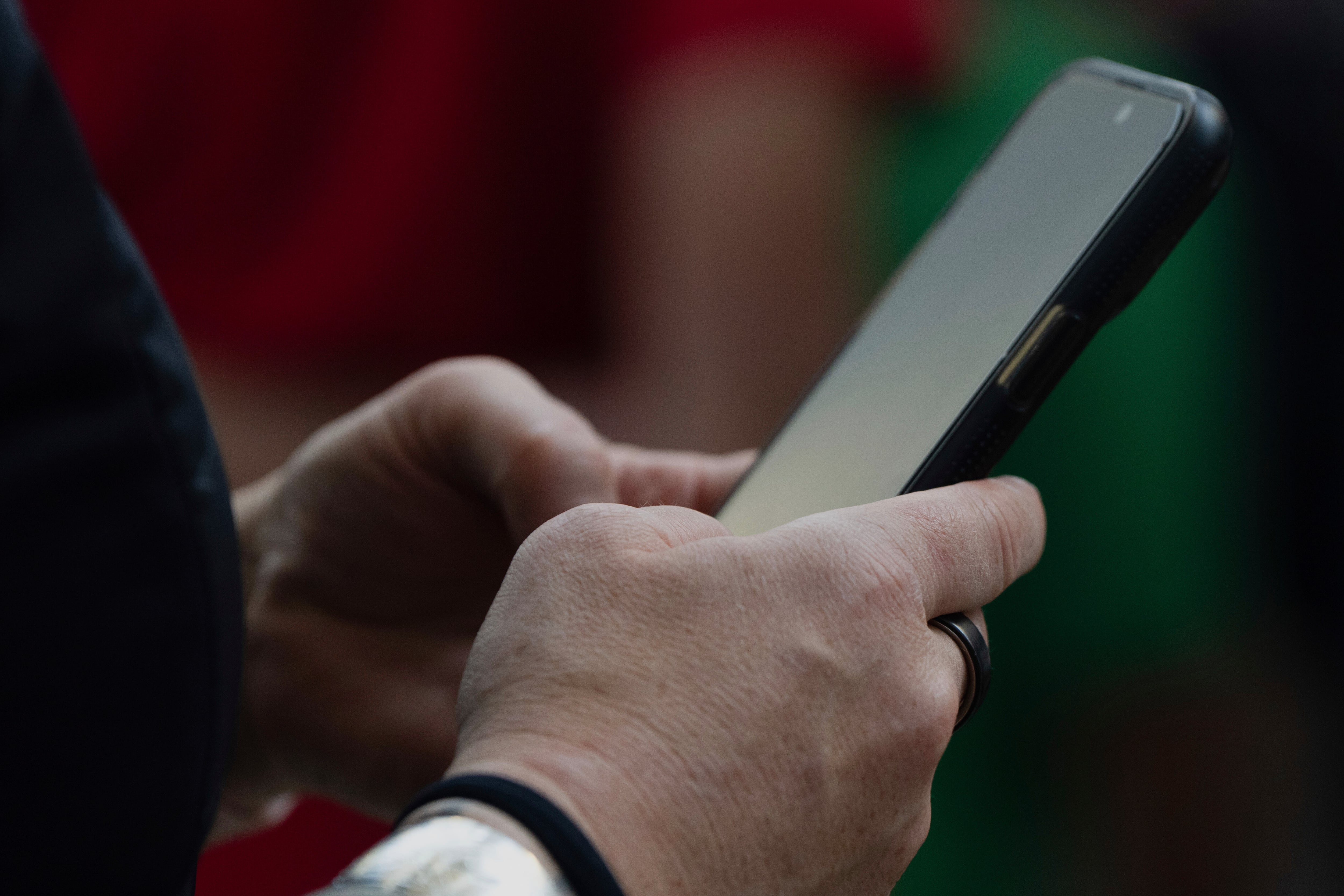 FILE - The scams start innocuously, often with a tailor-made text or WhatsApp message, and the scammers take time to build trust with the victim before cashing in on the relationship. A person looks at their phone at Seattle–Tacoma International Airport in this Sunday, June 1, 2025 file photo.
