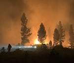 In this photo provided by the Bootleg Fire Incident Command, a firefighter and rig work through the night, July 17, 2021 at the Bootleg Fire.
