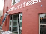 A sign writer adds the finishing touches to the newly opened North By Northeast Community Health Clinic.