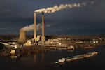FILE - A barge on the Ohio River moves past the Mountaineer Power Plant, a coal-fired power plant near New Haven, W.Va., March 13, 2026.