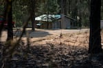 A bulldozer line protects a property just beyond charred trees and dirt burnt in the Grasshopper Fire in the unincorporated community of Sportsman Park, Ore.