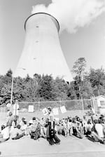 FILE - A handful of demonstrators along with newsmen gather at the entrance to the nuclear power plant, Trojan, at Rainier, Ore., Aug. 6, 1977, to protest the use of nuclear power. The demonstration remained peaceful as authorities made no effort to remove the protesters. The cooling tower looms in the background.