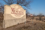 The town sign of Muscatine, Iowa, an agricultural community hours away from public universities.