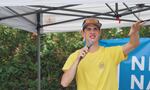 A man in a yellow shirt and hat holding a microphone.