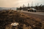 Acres of burned land from the Bench Fire surrounds cars driving on Highway 26 between Warm Springs and Madras, Ore., on July 27, 2026.