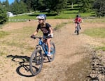 Eleanor Baker, left, and Taj Fields, right, ride mountain bikes on June 7, 2024, behind the Nestucca K-8 School, which is part of the local school district in southern Tillamook County near Cloverdale. Supporters of a proposed nearby mountain biking system hope it will help connect young people with nature.