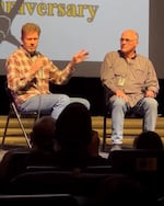 Two men sit on a stage at a convention.