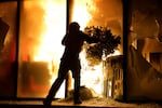 A hooded protester vandalizes the Justice Ministry during clashes in Tirana, Albania, Wednesday, Oct. 14, 2026, as students joined the Flamingo anti-government movement.