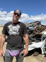 Gambler 500 organizer Tate Morgan poses in front of multiple abandoned cars that were removed from public lands as part of the Gambler 500 2026.