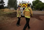 Firefighters walk back to their truck after filling up with water at Matt Cyrus's (not pictured) farm in Cloverdale, Ore., on Aug., 25, 2025. Cyrus's farm is one of the water and gas filling stations for firefighters working on the Flat Fire.