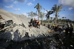 Residents and civil defense teams carry out a search and rescue operation around the rubble of the building demolished after an Israeli attack in Deir al Balah, in central Gaza, on Jan. 26.