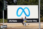 People talk near a Meta sign outside of the company's headquarters in Menlo Park, Calif., March 7, 2023. (AP Photo/Jeff Chiu)