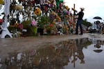 Roberto Marquez places a cross at a memorial wall for flood victims, Sunday, July 13, 2025, in Kerrville, Texas.