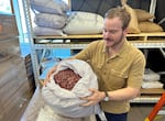 Seth O’Malley shows off a bag of dried rose petals used by Wilderton at their distillery and tasting room in Hood River, Ore. on August 2, 2023. As the founding distiller, O’Malley says he sources ingredients for the nonalcoholic botanical spirit from six continents.