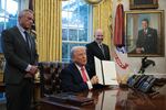 President Trump, joined by Health and Human Services Secretary Robert F. Kennedy Jr. (left) and Commerce Secretary Howard Lutnick, signs an executive order in the Oval Office on Tuesday.