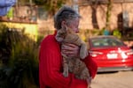 Denise Johnson, whose home is one of the few that survived the Eaton Fire in her neighborhood in Altadena, Calif., holds her cat Ramsey as she and her two children hunker down without power to care for their pets and protect the home Tuesday, Jan. 14, 2025.