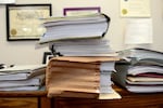 Folders containing documents related to immigration cases are piled on a table in the office of Stephen Born, Esq. on July 31, 2025 in Everett, Mass.