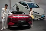 FILE - Models stand next to a latest EV car from Chinese automaker BYD showcased at the Auto China 2026, in Beijing, April 25, 2026.