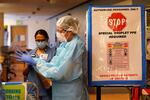 Registered nurse Diane Miller pulls on gloves and other protective equipment as she prepares to enter patient rooms in the COVID acute care unit at UW Medical Center-Montlake, Tuesday, Jan. 26, 2021, in Seattle.