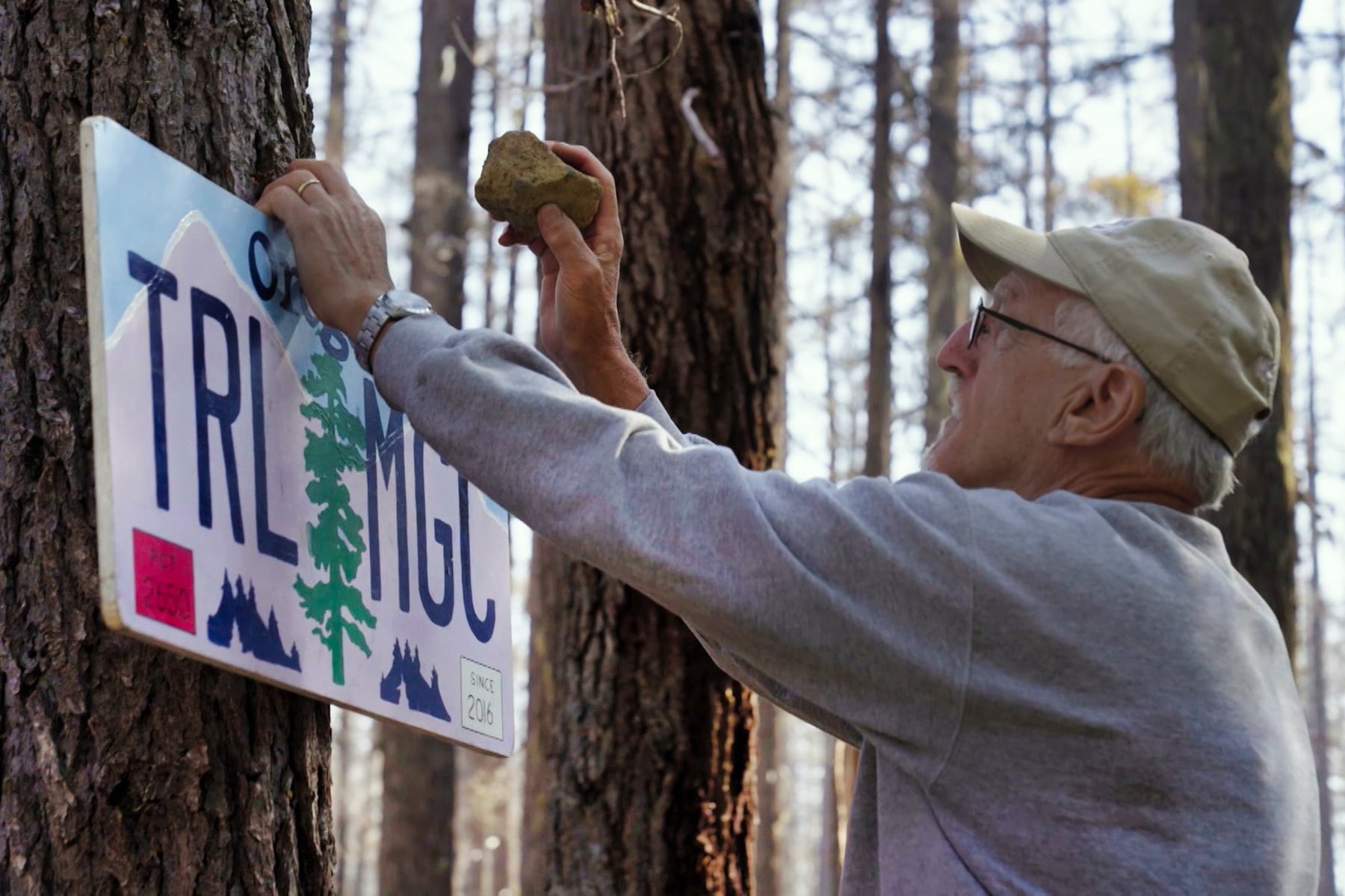 Harold Leeson puts up a trail magic sign along the Pacific Crest Trail near Charlton Lake in Oregon's Cascade Range on Aug. 9, 2024.