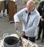 Coos Bay Mayor Joe Benetti puts soil from where the lynching of Alonzo Tucker took place in 1902 into a jar for display.