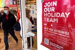 A holiday season hiring sign is displayed at a retail store's entrance.