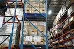 Boxes stacked up to the ceiling containing meat sits in a refrigerated warehouse at Sysco's distribution center.