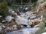 Netting made from mettle cables is visible above a creek in Montecito, Calif., on Jan. 12, 2023. With climate change predicted to produce more severe weather, officials are scrambling to put in basins, nets and improve predictions of where landslides might occur to keep homes and people safe.