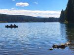 Two people can be seen in a small boat on a lake under a bright blue sky.