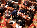 Members of the Missouri House — some wearing masks, and other not — huddle closely in conversations before the beginning of session on Wednesday, Feb. 3, 2021, in Jefferson City, Mo. The House chamber has no mask mandate and has not modified its seating during the coronavirus pandemic. The House canceled all work for a full week in January after a COVID-19 outbreak.