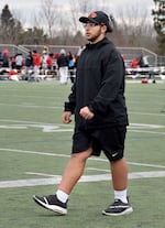 A student in a black outfit and pair of shorts walks on a field.