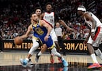 Golden State Warriors guard Stephen Curry is defended by Portland Trail Blazers guard Ashton Hagans, center, and center Duop Reath, right, during the second half of an NBA basketball game in Portland, Ore., Thursday, April 11, 2024. The Warriors won 100-92.