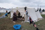 A 26-year-old pregnant woman named Talibe Gezginci cleans her tent in a makeshift camp for displaced people in Gaziantep.