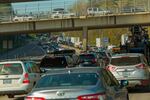 Cars are seen filling multiple lanes of traffic on a highway or interstate, while more cars cross above them on an overpass.