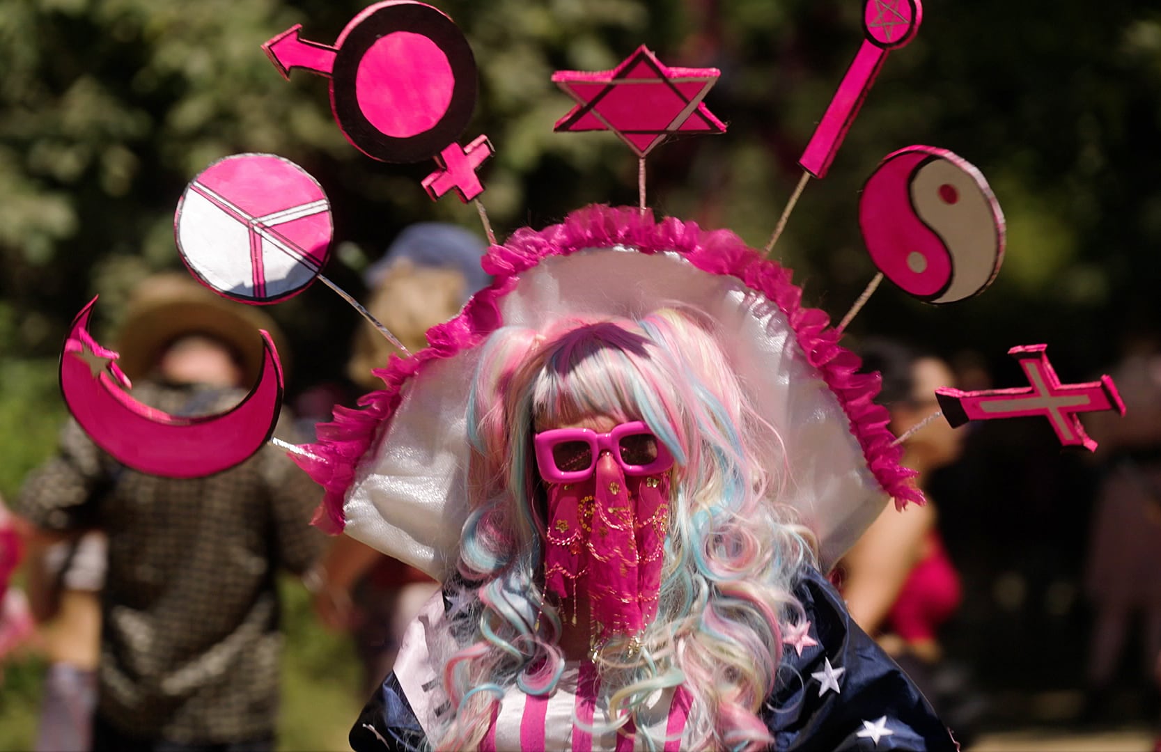 A fair-goer displays the ethos “COEXIST” as a costume in July 2024. This 21st century expression is a modern version of the 1960s hippie focus on peace and love.