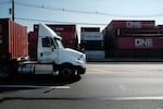 Trucks move past cargo containers at a port in Bayonne, N.J., in 2021. The state is adopting California's Advanced Clean Trucks rules, which require at least 7% of medium- and heavy-duty vehicles sold in the state to be zero-emission for model year 2025. Dealers are petitioning for a delay, so far unsuccessfully.