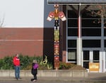 In this Feb. 23, 2021 photo, two staff members of Madison Middle School stand outside an entrance with a newly-installed totem pole made by the 4J NATIVES program.