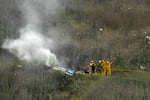 Firefighters work the scene of a helicopter crash where former NBA basketball star Kobe Bryant died in Calabasas, Calif., on Jan. 26, 2020. Bryant's widow is taking her lawsuit against the Los Angeles County Sheriff's Department and Fire Department to a federal jury seeking compensation for photos deputies shared of the remains of the NBA star, his daughter and seven others who died in the crash.